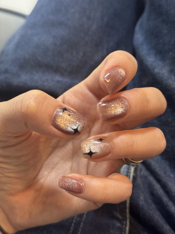 Nude shimmer nails with gold glitter and star accents